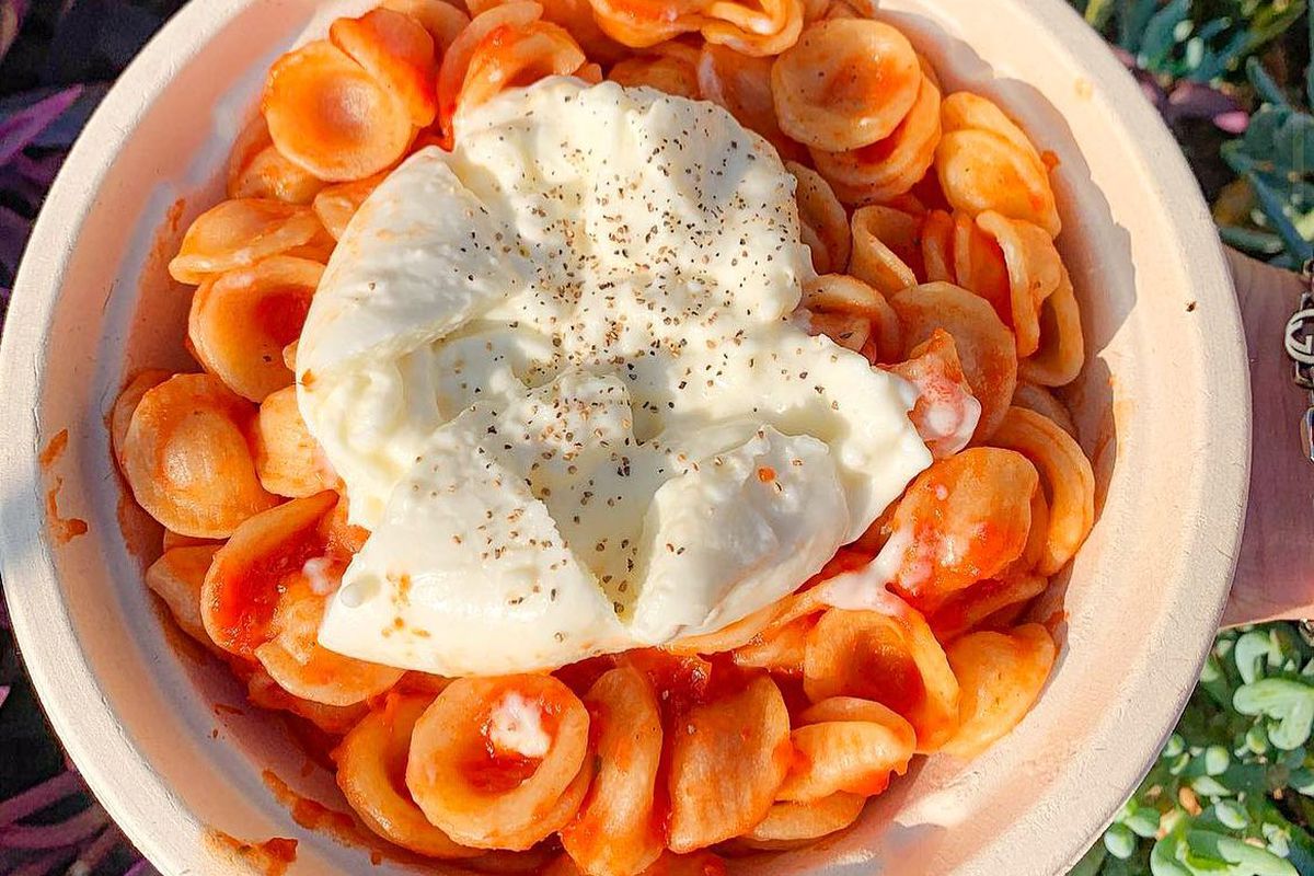 A bowl of red-sauce pasta with a glob of white burrata cheese in the middle. 