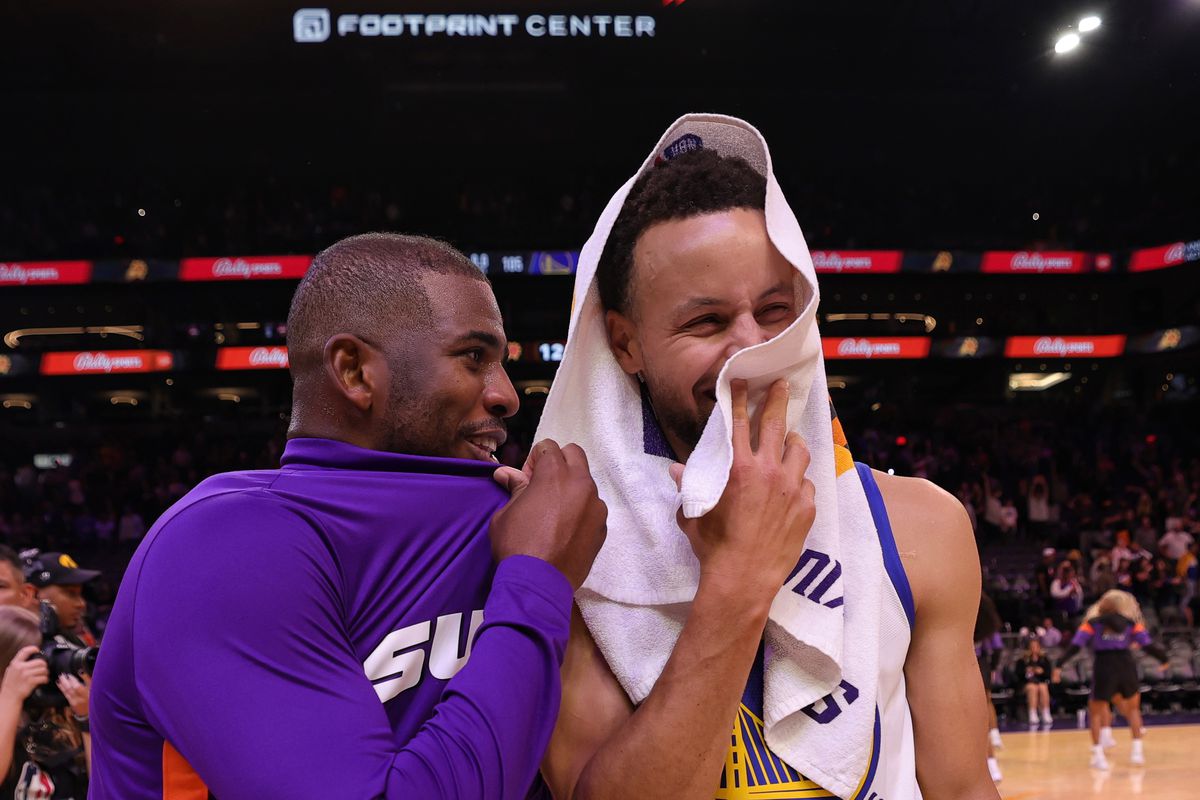 Chris Paul talking to Steph Curry, who is laughing, after a game