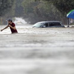 Moses Juarez, left, and Anselmo Padilla wade through floodwaters from Tropical Storm Harvey on Sunday, Aug. 27, 2017, in Houston, Texas.