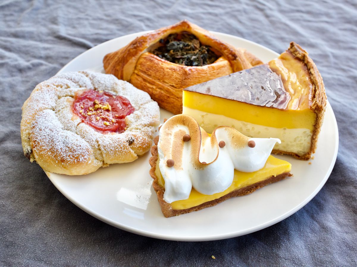 A plate of four pastries, including slices of pie and two roll-like pastries with fruit fillings.