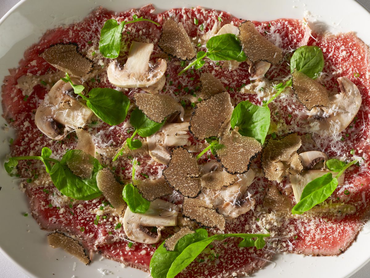 A plate of beef carpaccio with mushrooms and Italian parsley.