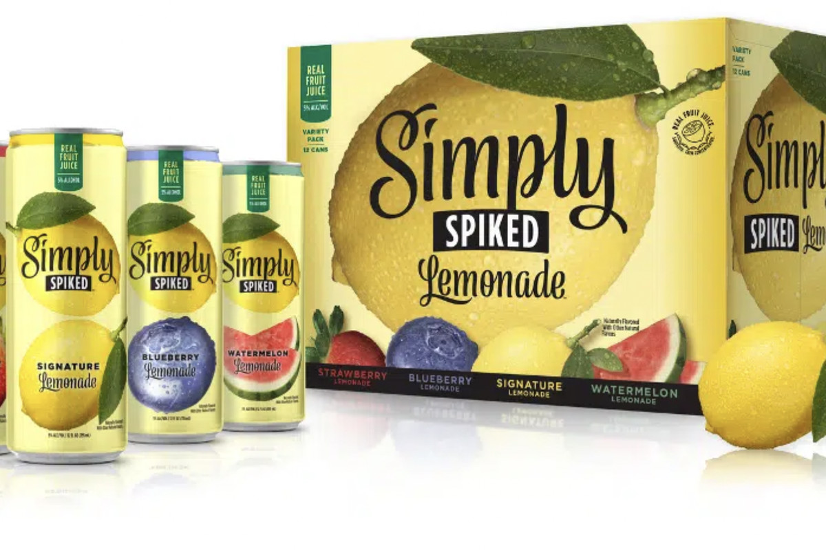 Four yellow cans of Simply Spiked hard lemonade with a lemon logo next to a box with the same logo and brand name, on a white background.