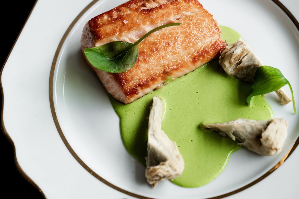 A filet of salmon and sorrel on a white plate.
