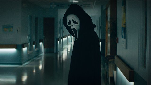 Ghostface stands in a high school hallway in Scream (2022)