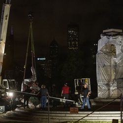 A crane lowers the Christopher Columbus Statue to the ground in Grant Park, Friday, July 24, 2020.