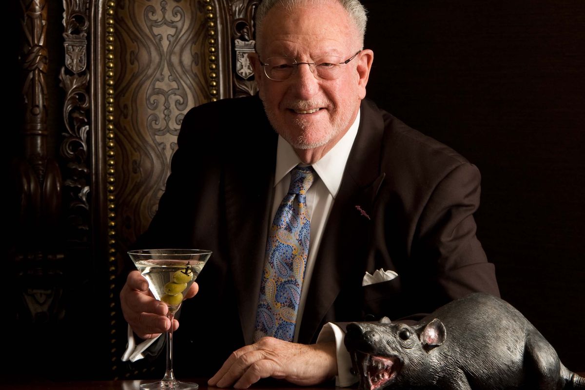 A man in a suit holds a martini glass