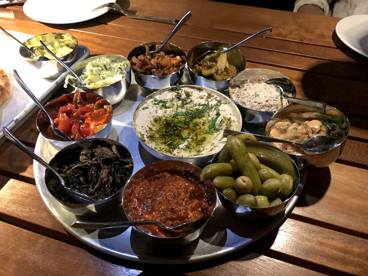 A metal platter with small metal bowls filled with various dips.