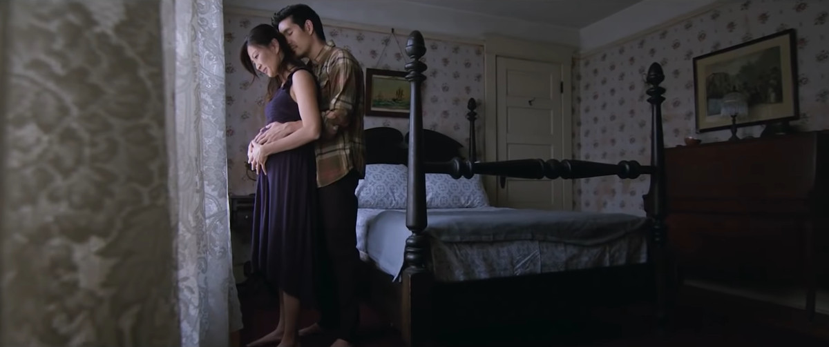 Couple hugging in front of a bed in their movie Live in Gray