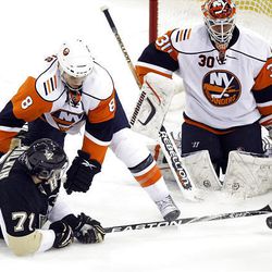 Pittsburgh Penguins' Evgeni Malkin, left, of Russia, tries to get the puck past New York Islanders goalie Dwayne Roloson, right, as he is checked by New York Islanders' Bruno Gervais in the first period. Malkin did not score.
