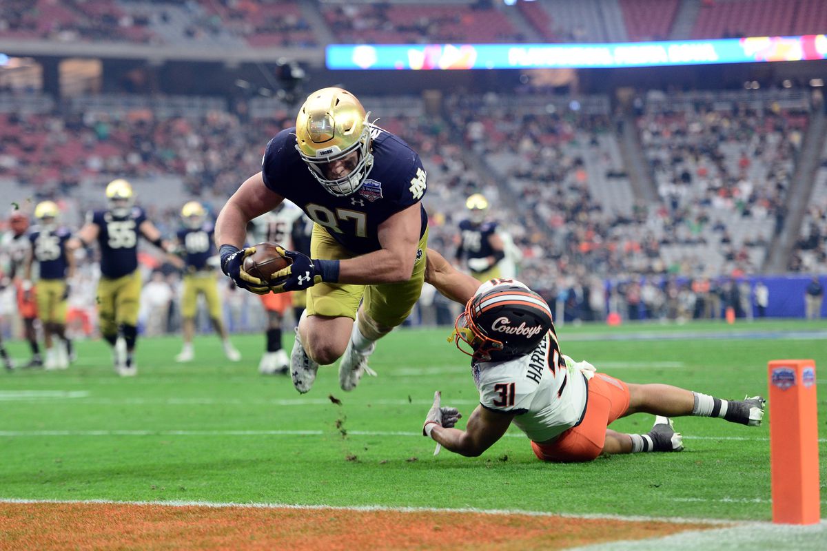 Notre Dame Fighting Irish tight end Michael Mayer dives past Oklahoma State Cowboys safety Kolby Harvell-Peel for a touchdown during the first half of the 2022 Fiesta Bowl at State Farm Stadium.