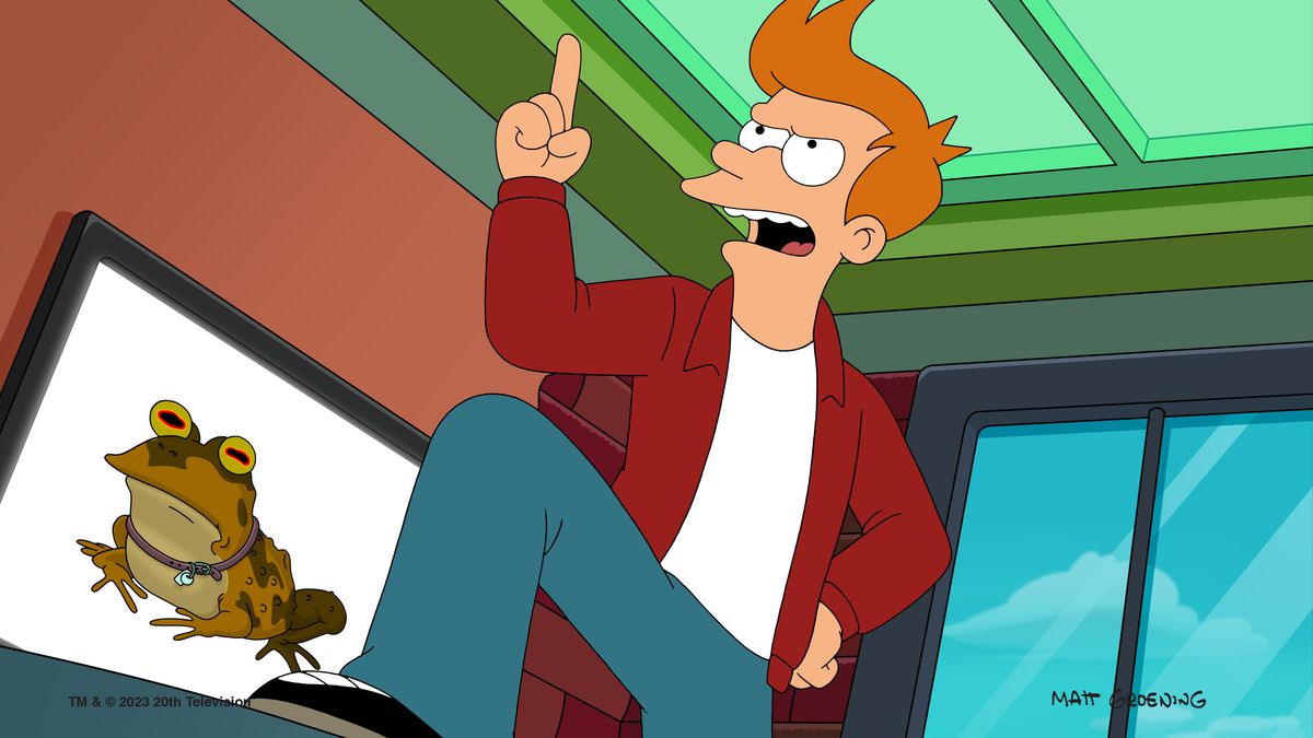 Fry standing with his foot up on a desk speaking