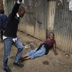 A relative wails on the floor of an alleyway near to the body of a man who had been shot in the head and who the crowd claimed had been shot by police, in the Mathare slum of Nairobi, Kenya Wednesday, Aug. 9, 2017. Kenya's election took an ominous turn on Wednesday as violent protests erupted in the capital. (AP Photo/Ben Curtis)