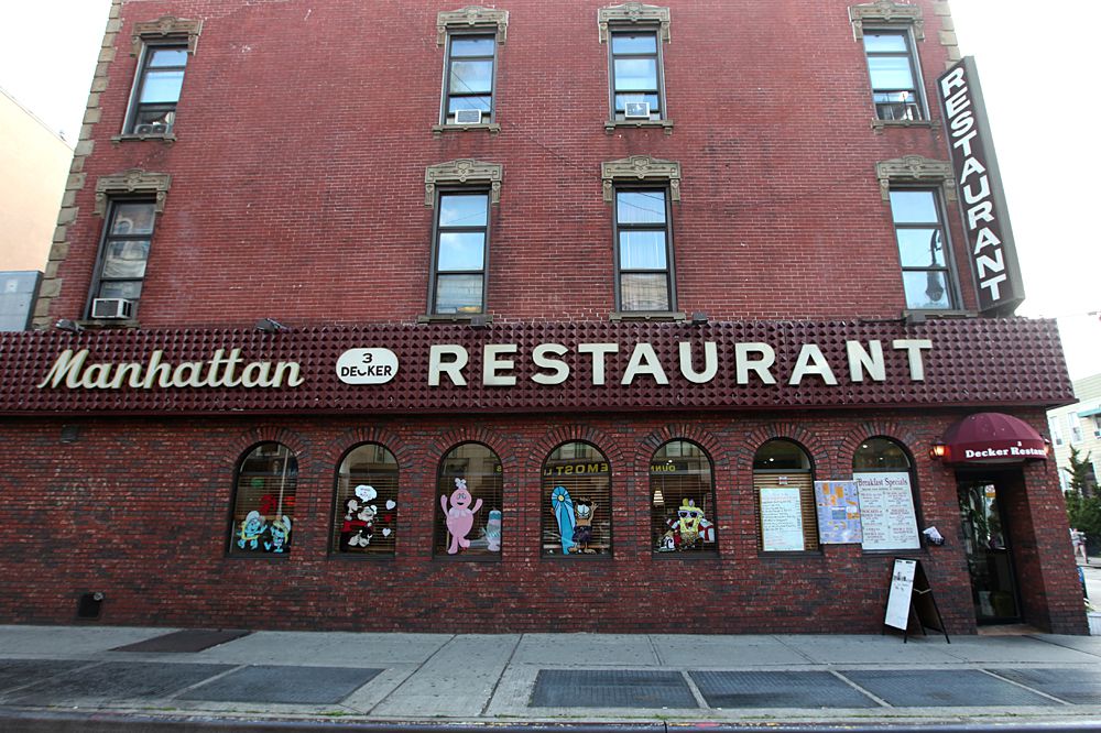A tall brick building with a sign that says “Manhattan Three Decker Restaurant.”