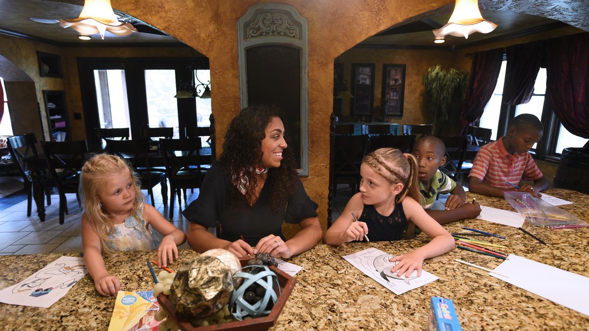 Shamber Flore, 20, center, talks and colors with younger siblings Jubilee, 7, Mercy, 9, Marcus, 10, and Lucas, 10, left to right, in the family's kitchen and dining room area at home in DeWitt, Michigan, on June 18, 2018. The Flore family has adopted thro