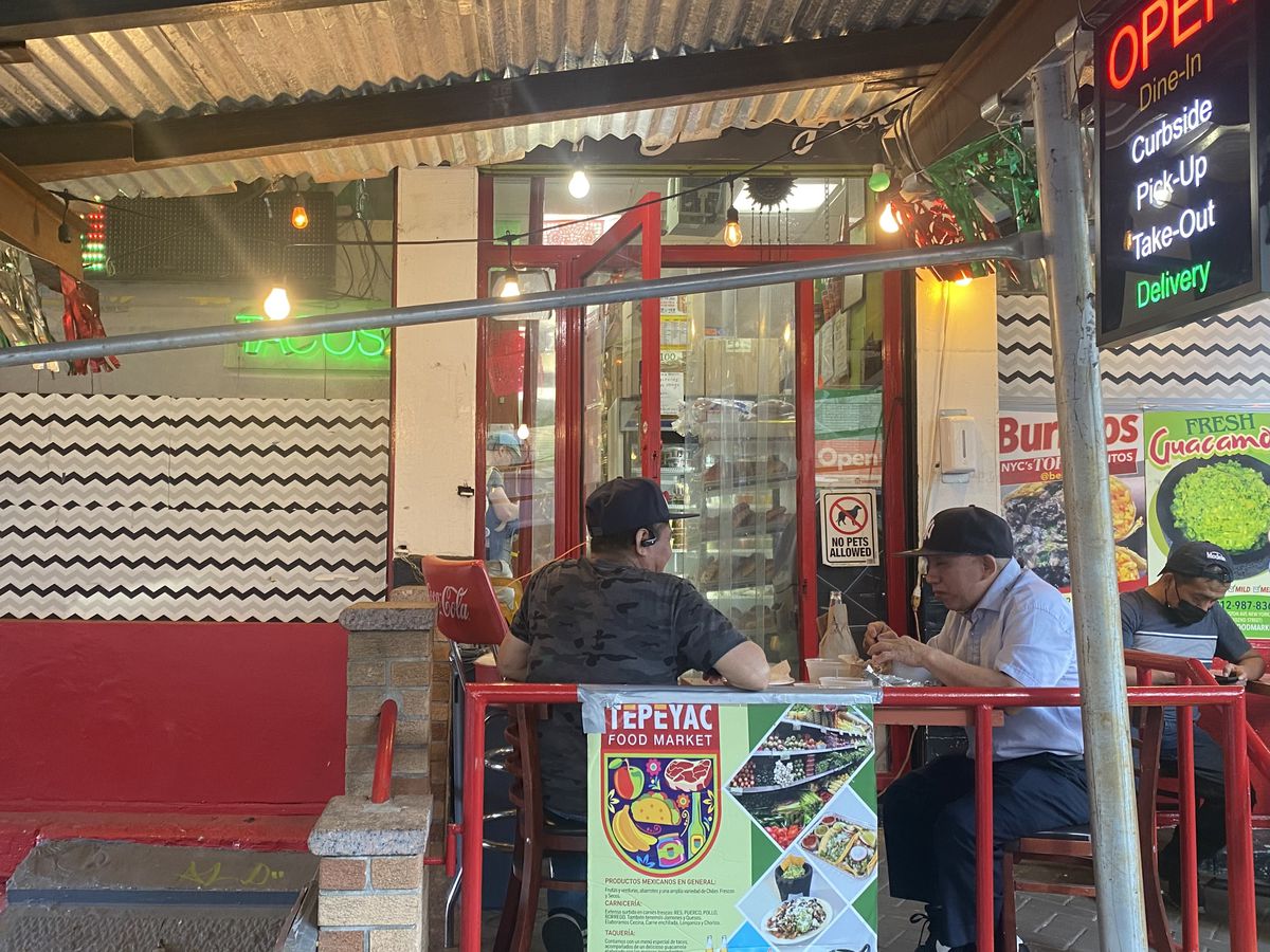 Customers sit at a table outside of El Tepeyac Food Market.