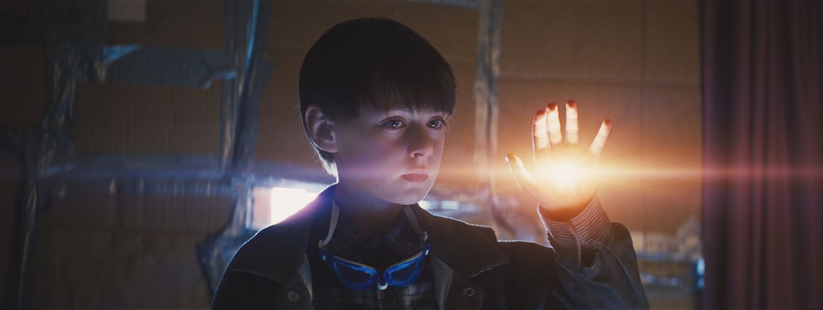 A child (Jaedan Martell) stands in a darkened room with a light glowing from his palm.