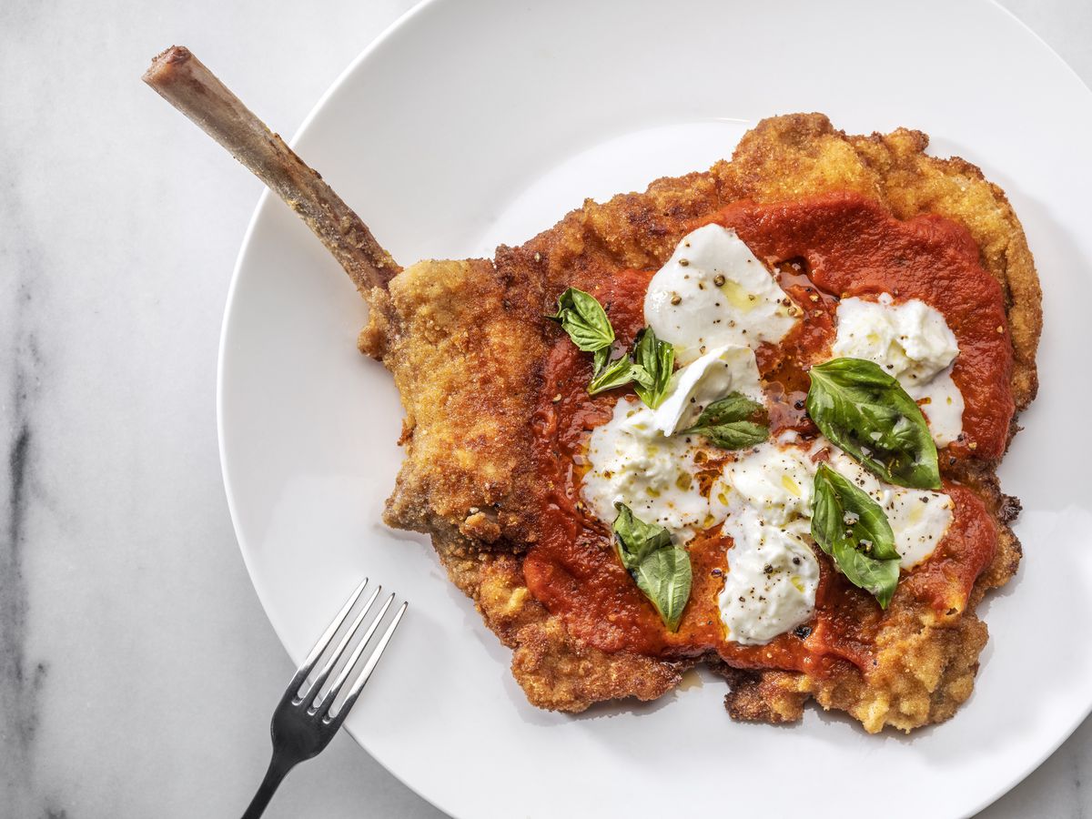 A bone-in, breaded veal covered in tomato sauce, large pieces of mozzarella cheese, and torn basil.&nbsp;  