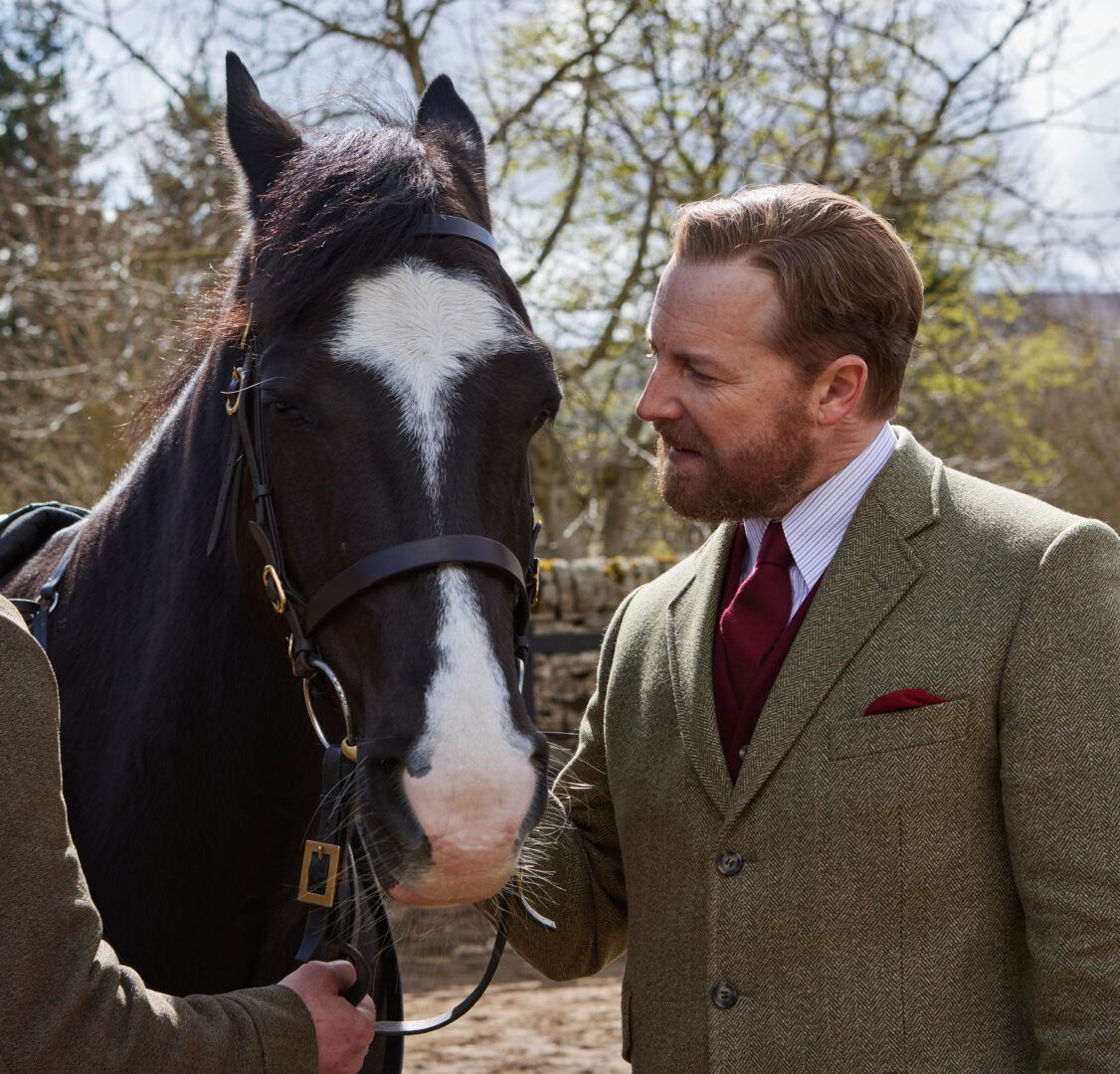 Siegfried wears a wool suit and looks adoringly at a horse in All Creatures Great and Small.