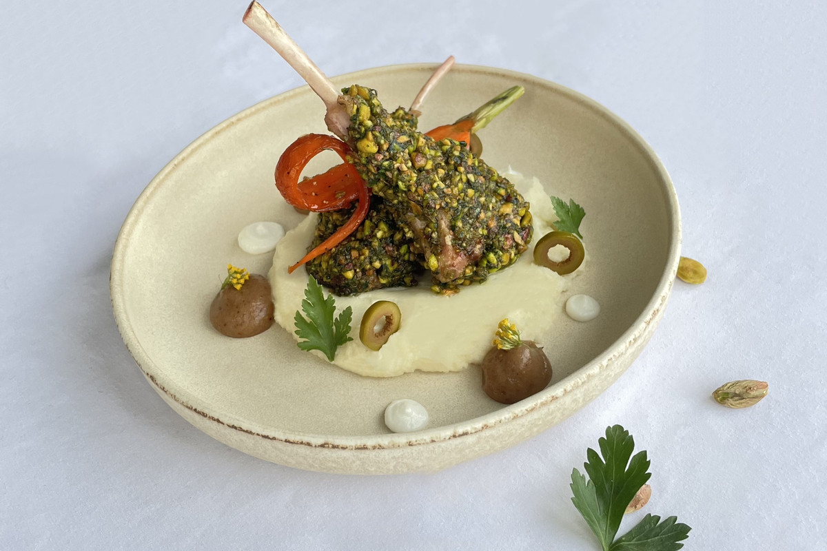 A round plate holds pistachio-encrusted lamb.
