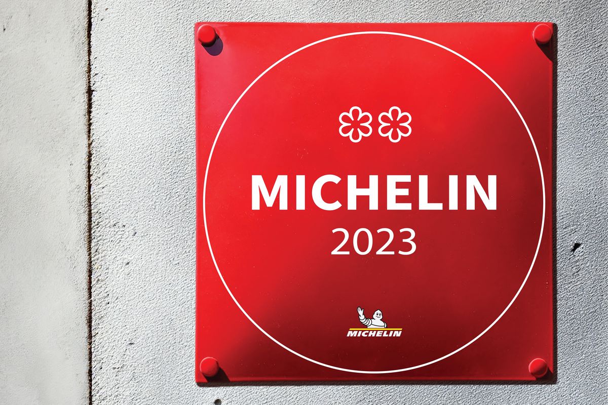 A red plaque posted outside of a restaurant displaying its Michelin ranking of two stars in 2023.