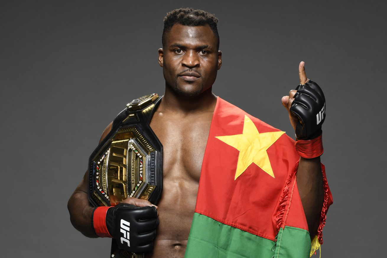 UFC heavyweight champion Francis Ngannou poses with his title belt and the flag of Cameroon after his fight at UFC 270.