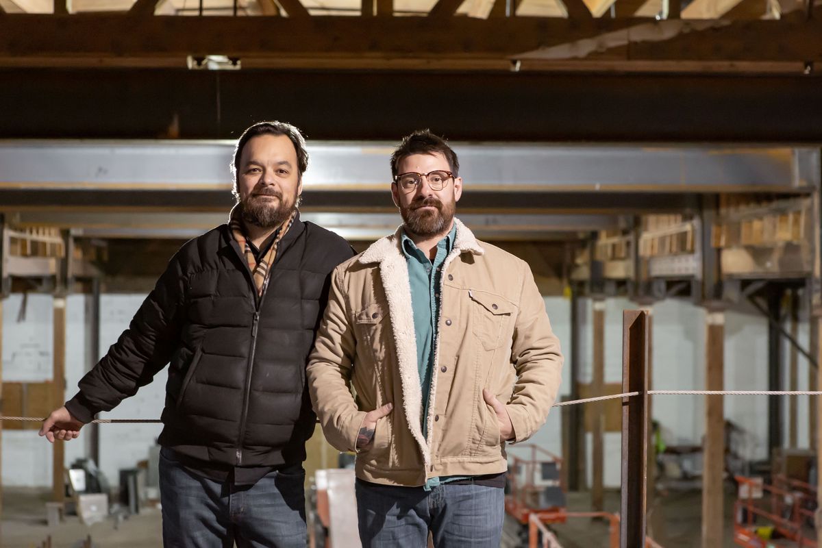 Jesse Held and Jeff Erkkila stand together, not smiling, in winter jackets on the site of their new distillery
