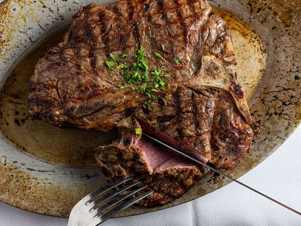 A 32-ounce t-bone steak on a patinaed metal plate.