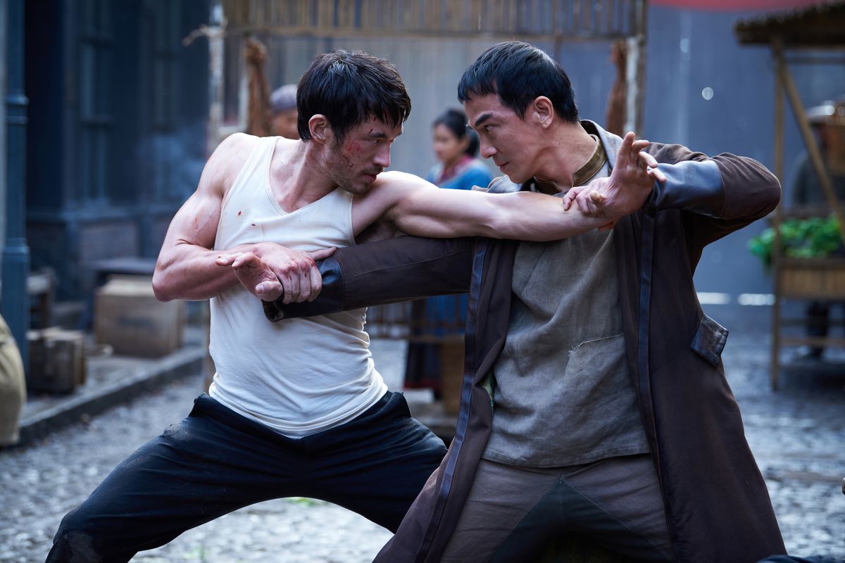Andrew Koji and Joe Taslim clasp each other’s arms while fighting, in an image that makes them look like an extension of each other, in Warrior.
