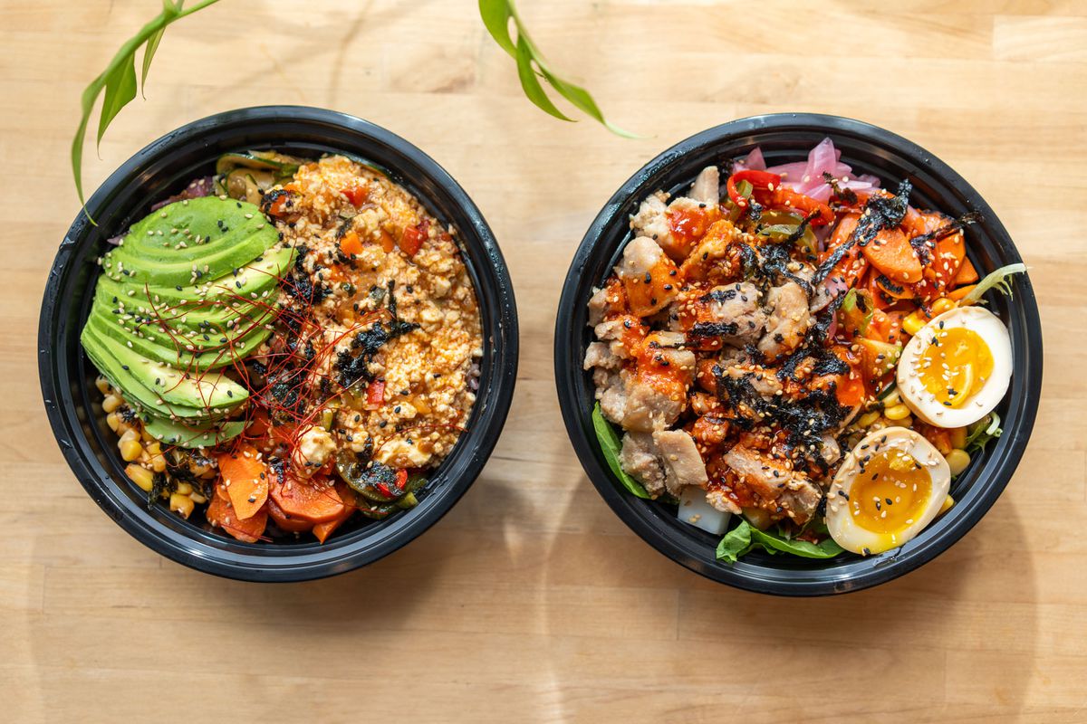 A pair of Korean rice bowls topped with egg and avocado.