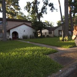 Patti Beller prays Thursday, July 10, 2014, in Spring, Texas, outside the home that was the scene of a multiple shooting the night before. The Harris County Sheriff's Office says Ronald Lee Haskell was booked Thursday on a capital murder/multiple murders charge and held without bond. Authorities believe Haskell fatally shot two adults and four children on Wednesday night and critically wounded a 15-year-old girl, who called 911. 