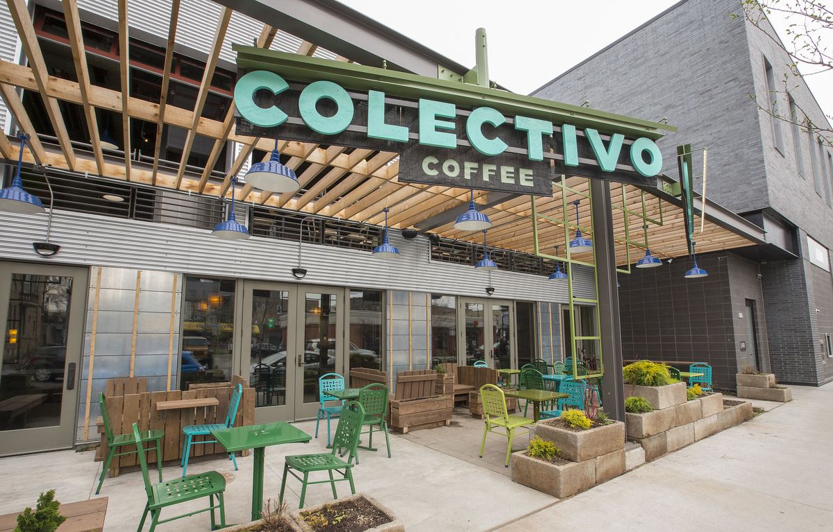Outdoor seating beside a large, industrial-style cafe with a large teal sign that reads “Colectivo Coffee”