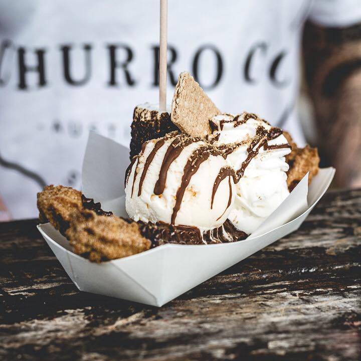 A churro in a basket with ice cream and chocolate drizzles.