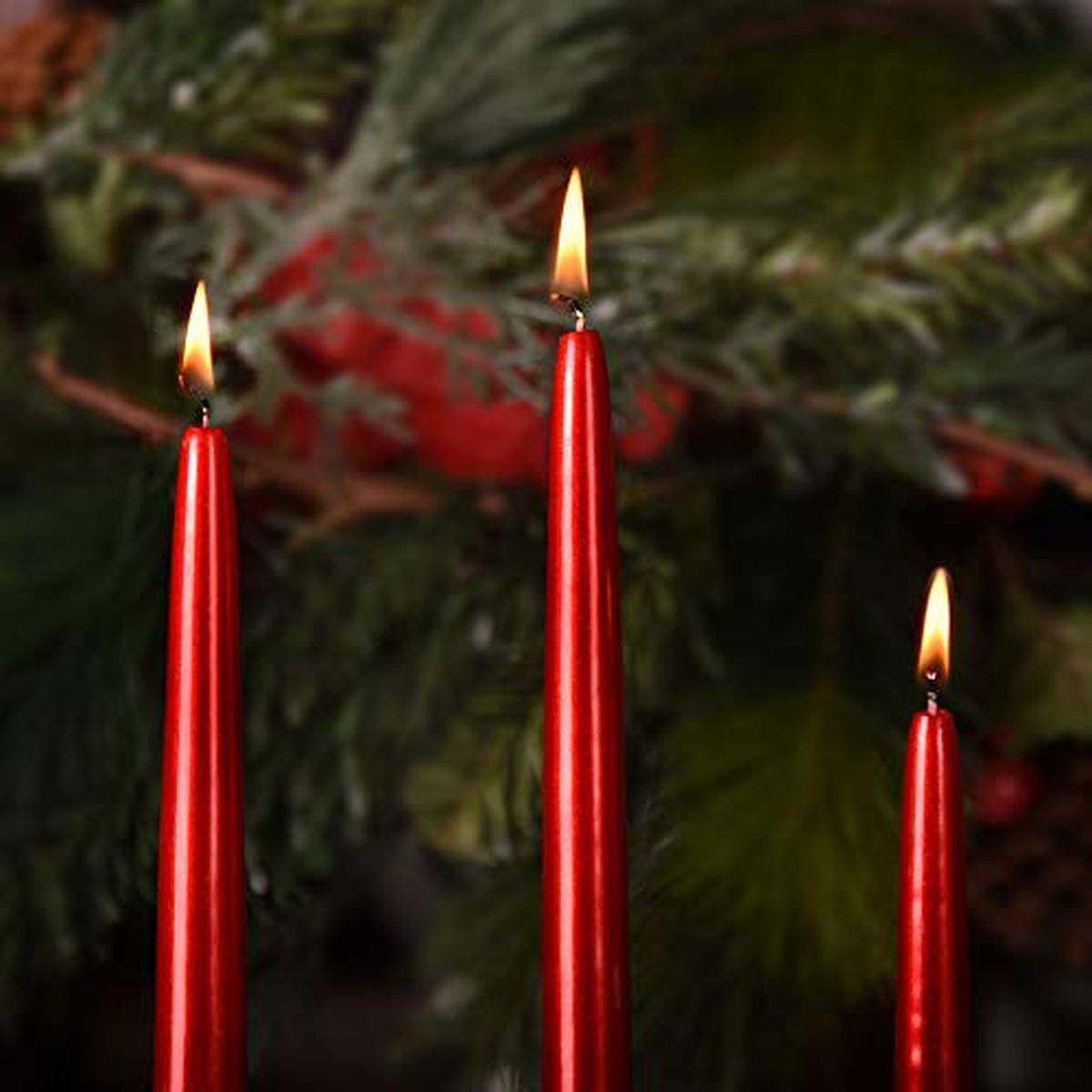 Three tapered red candles with flames. 