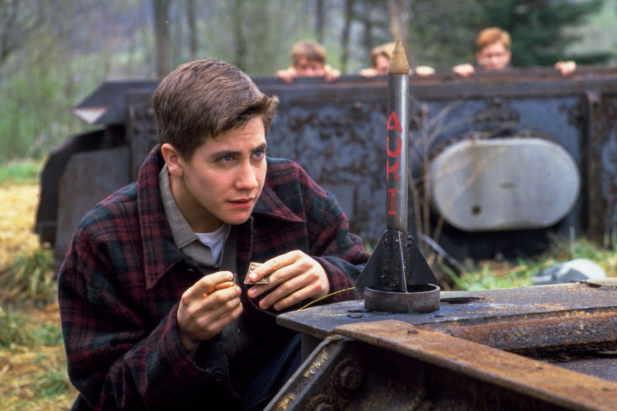 Homer Hickam (Jake Gyllenhaal) launches a model rocket with the letters AUKI on it as his friends watch from behind an overturned truck in October Sky