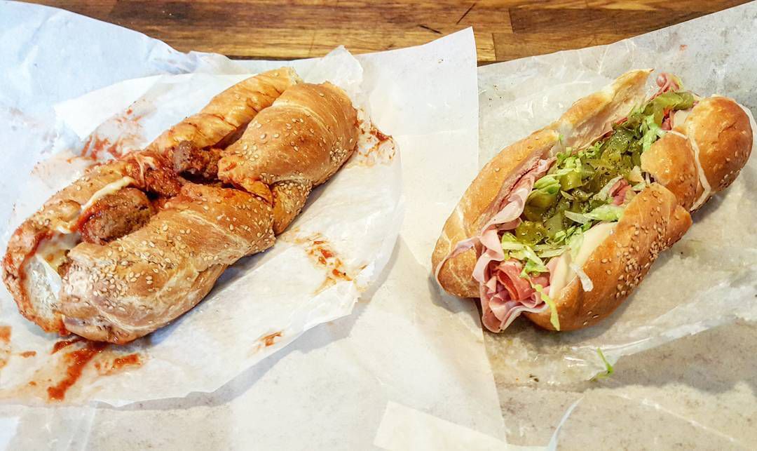 A meatball sub and an Italian sub on white deli paper