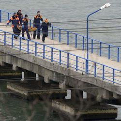 Russian rescue workers carry a body from the wreckage of the crashed plane, at a pier just outside Sochi, Russia, Sunday, Dec. 25, 2016. Russian ships, helicopters and drones are searching for bodies after a plane carrying 93 people crashed into the Black Sea. The plane was taking the Alexandrov Ensemble, a military choir, to perform at Russia's air base in Syria when it went down shortly after takeoff. 