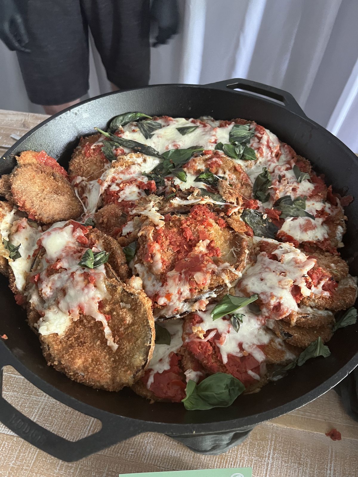 A pot holds slices of eggplant parmesan covered with marinara. 
