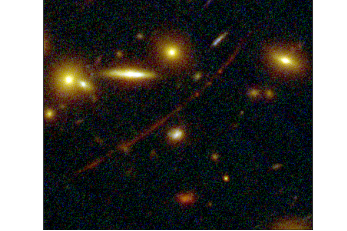 An image of galaxies against a dark background. An orange line arcs through the middle of the image. 