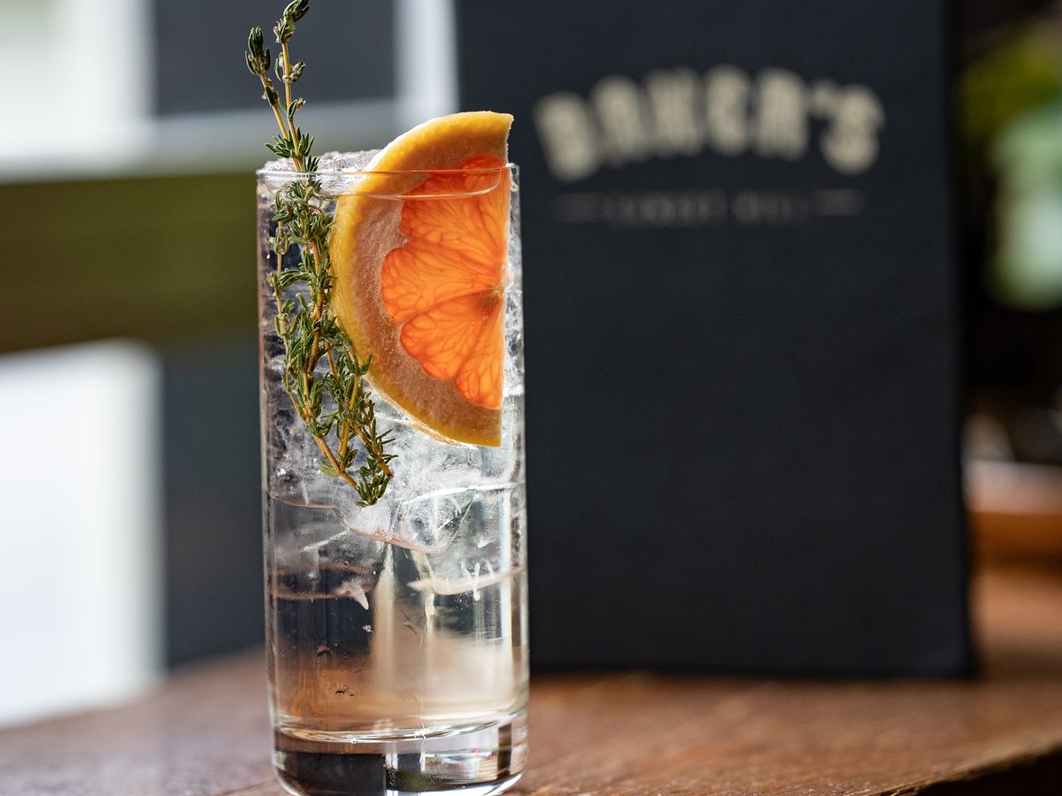 A cocktail garnished with grapefruit and thyme