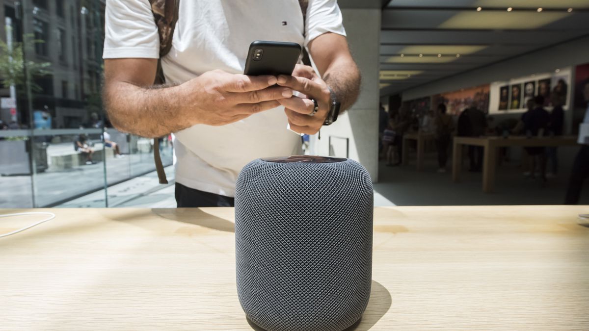 Man uses his phone to photograph a smart speaker