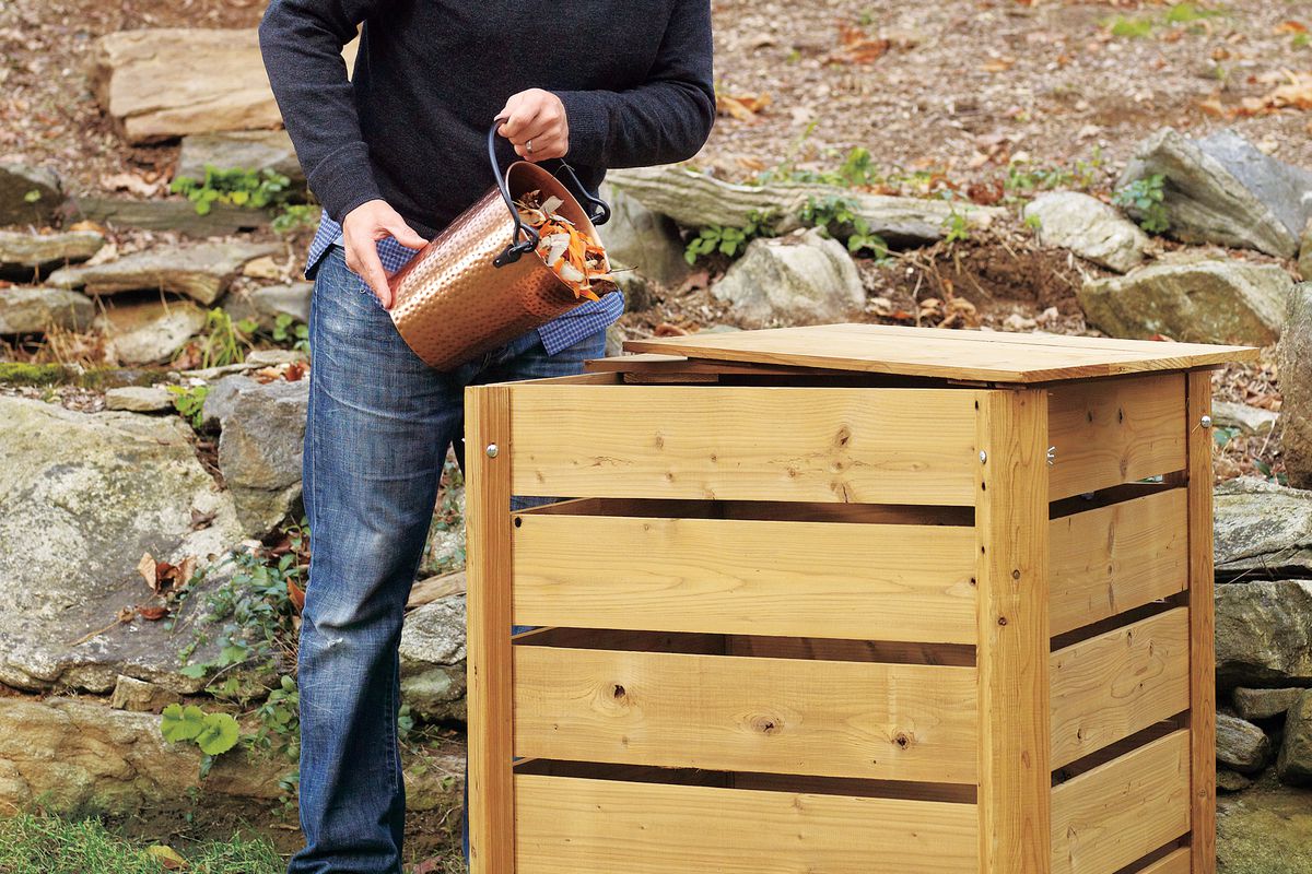 Man Dumps Material From Compost Pail Into Wooden Compost Bin