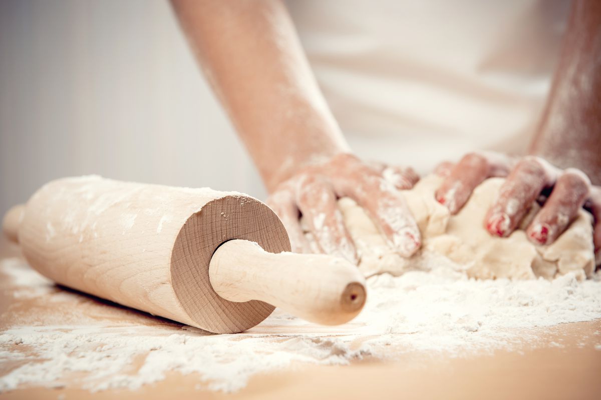 A woman kneads dough on a flour-covered surface