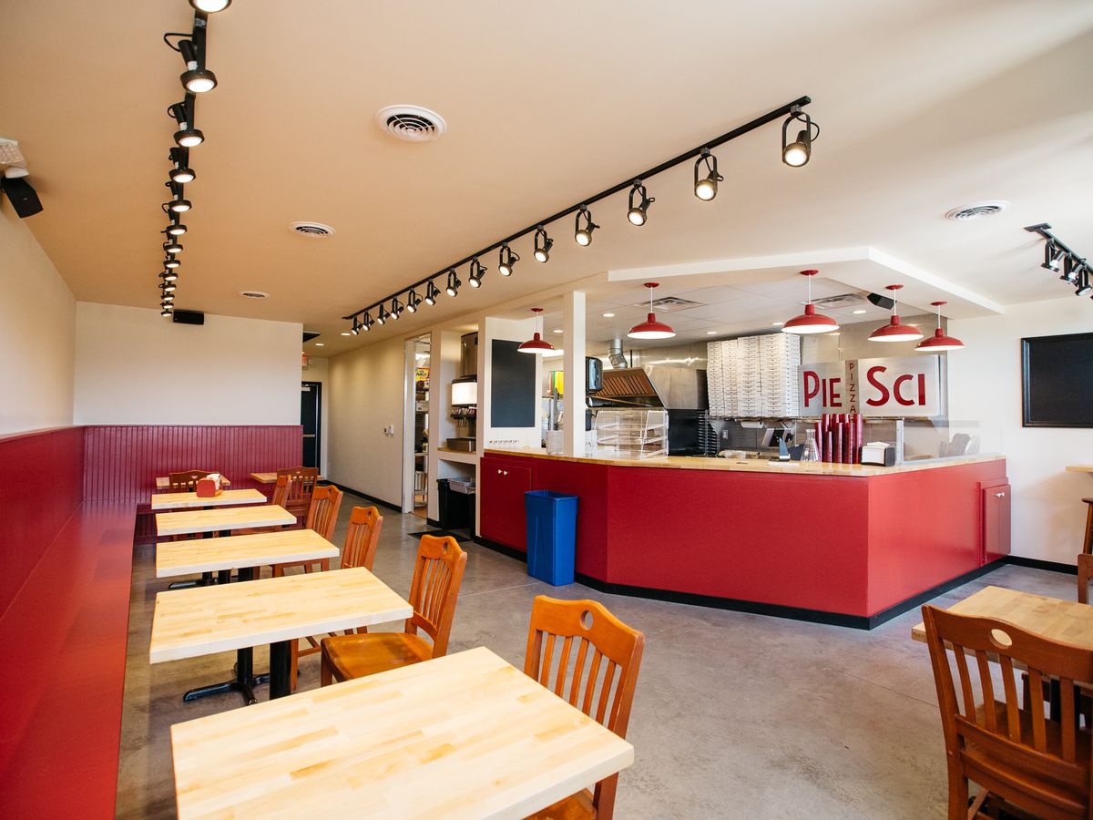 A wide view of two top tables along the wall in the red and white dining room at Pie-Sci