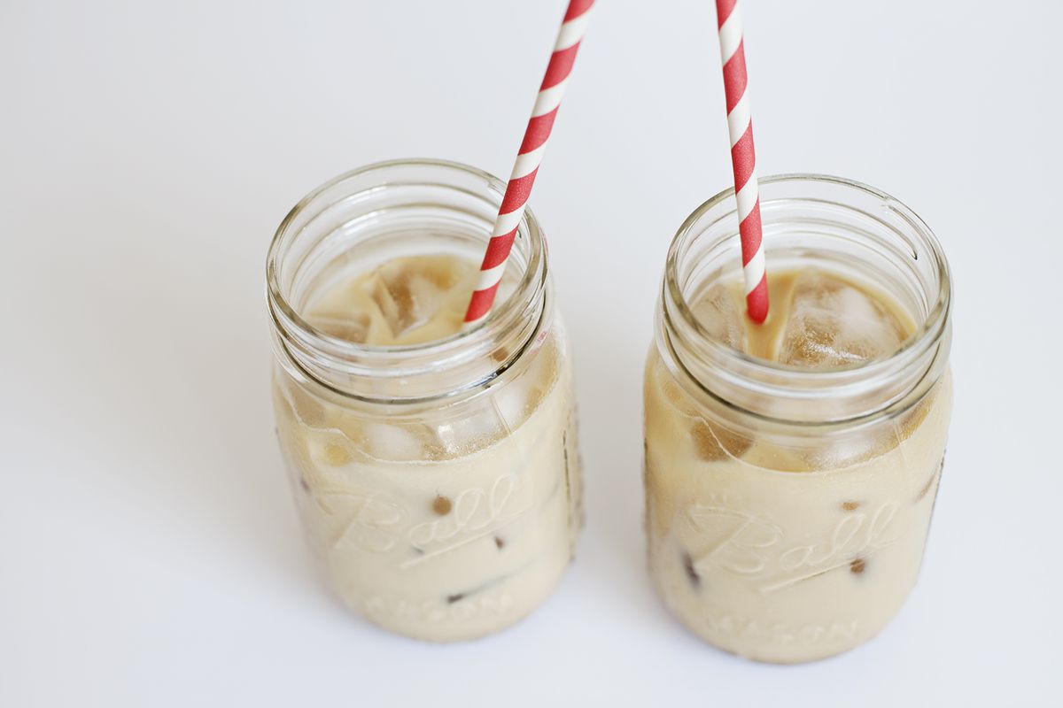 A glass of iced coffee with cream and a striped straw