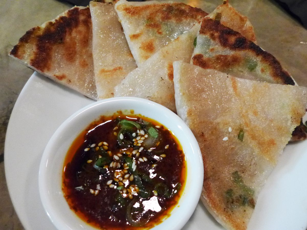 A fanned collection of pastry triangles with a spicy looking dipping sauce.