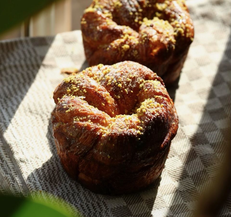 Two cardamom pistachio buns are seen in the sunlight.