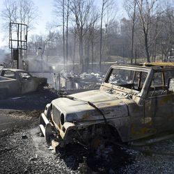 Smoke rises around the charred remains of two vehicles Tuesday, Nov. 29, 2016, in Gatlinburg, Tenn., after a wildfire swept through the area Monday. 