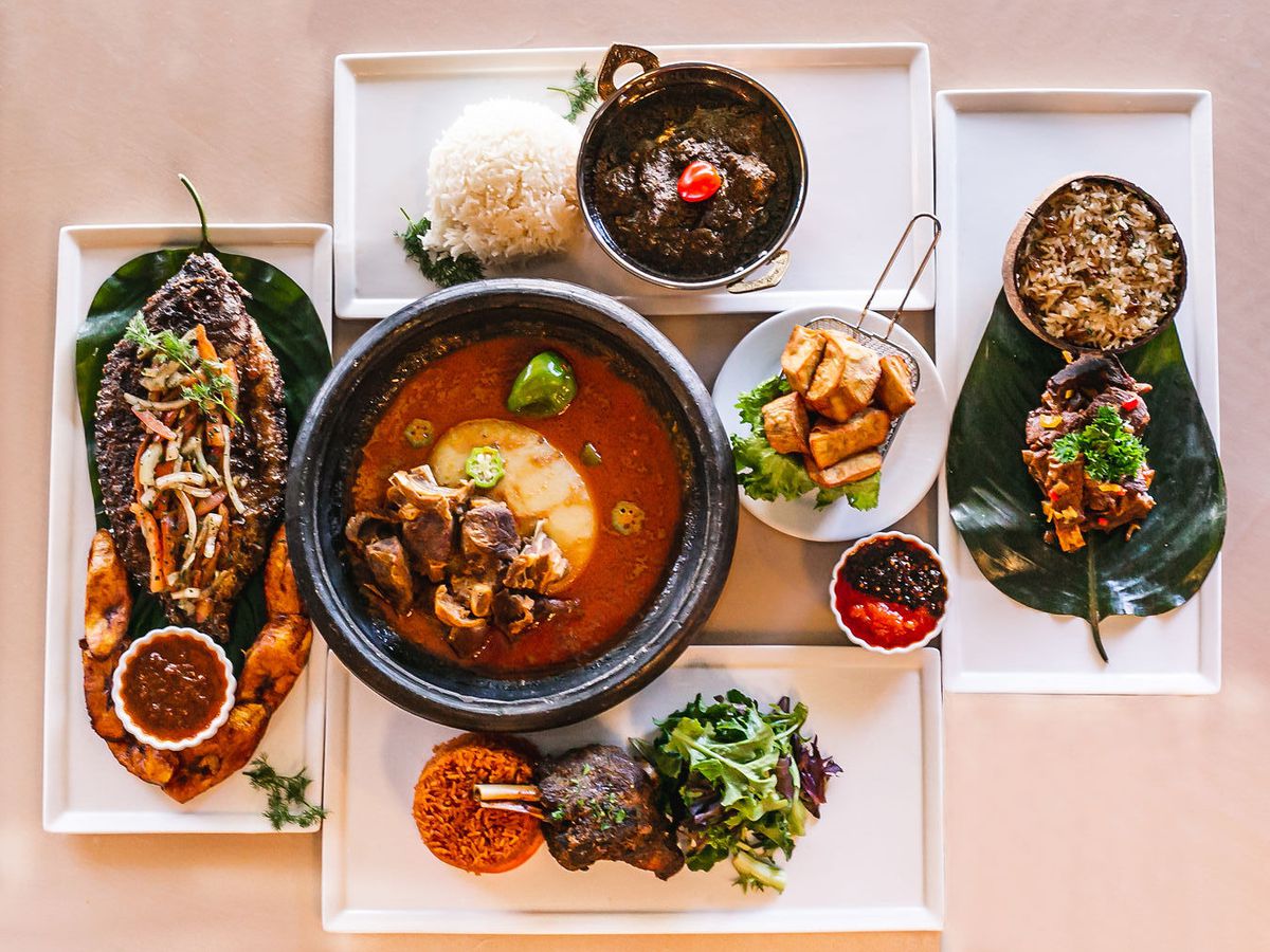 A top-down view of dishes, including soup, full roasted fish, meats, and stewed greens