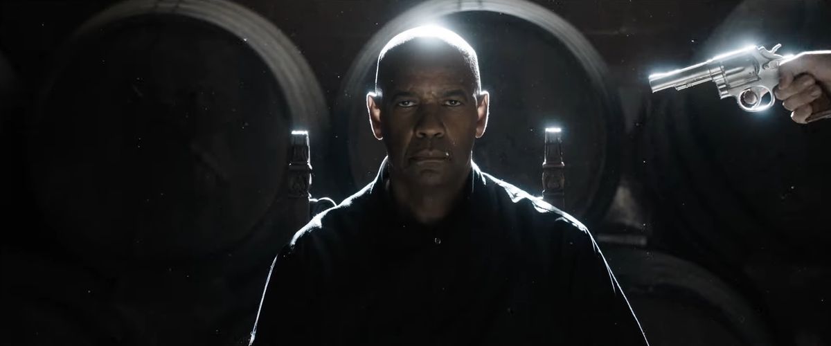Denzel Washington sits in a chair as a silver revolver points at him from his left in The Equalizer 3.