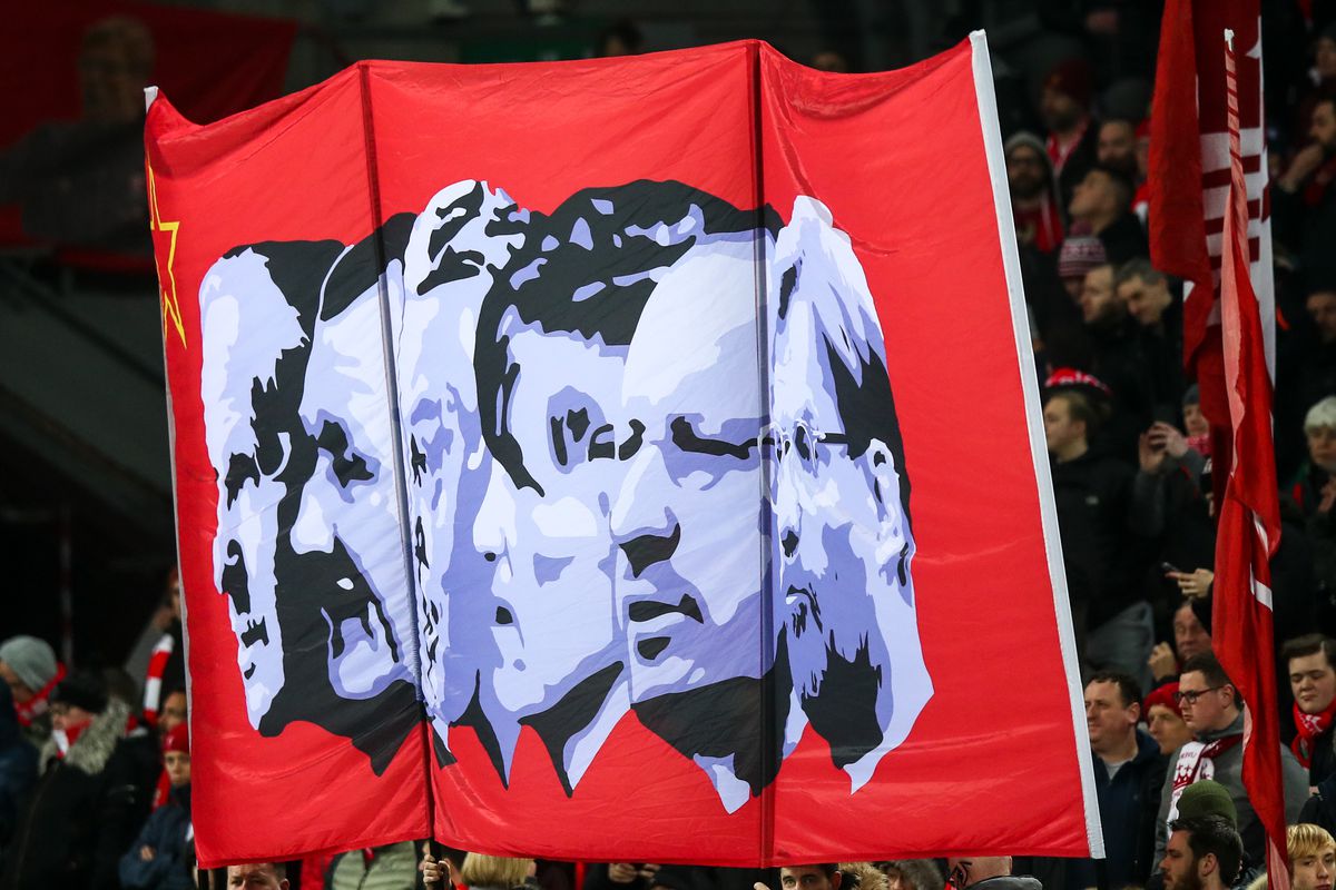 Fans at Anfield hold up a red banner featuring black and white images of past Liverpool managers, including Rafa Benítez.